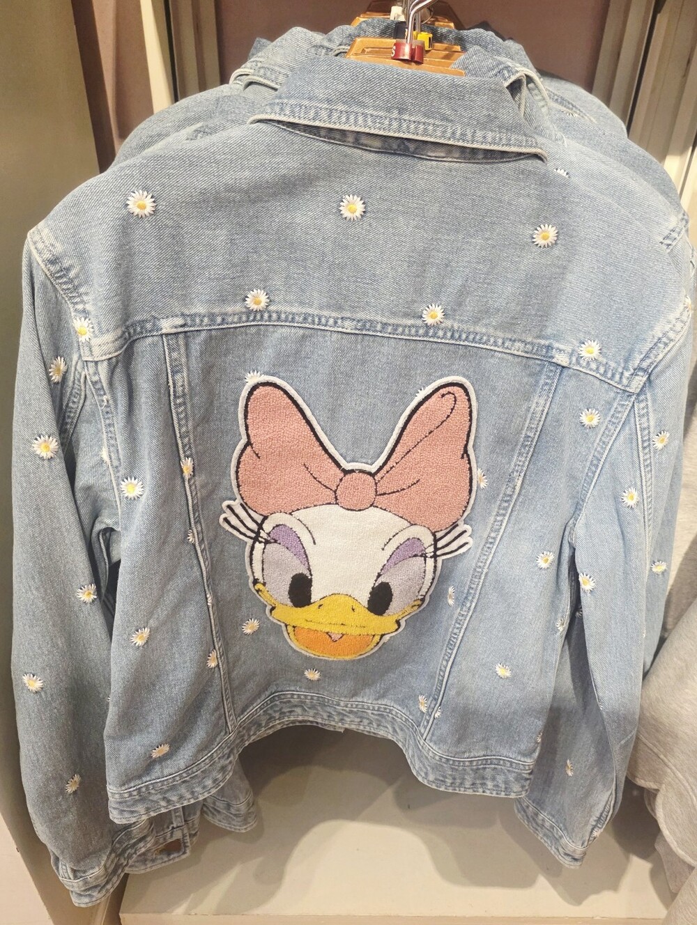 Disney Denim Jacket features an embroidered Daisy Duck back patch with scattered